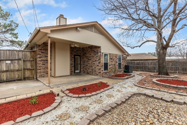 rear view of property featuring a patio area, a chimney, a ceiling fan, and brick siding