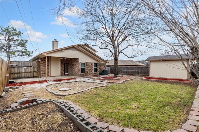 view of yard with a patio area, a fenced backyard, a fire pit, and an outdoor structure