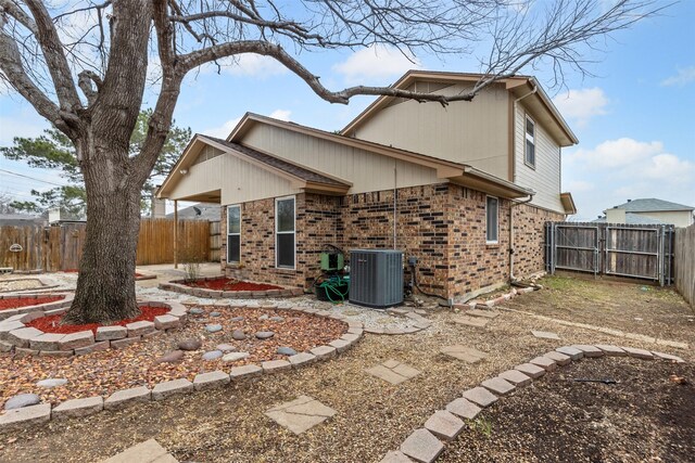 back of house with a fenced backyard, a gate, cooling unit, a patio area, and brick siding