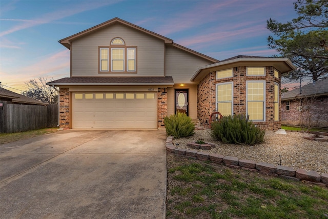 traditional-style house with a garage, brick siding, driveway, and fence