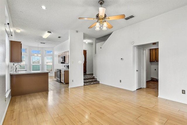 unfurnished living room featuring ceiling fan, light wood-type flooring, a sink, and visible vents