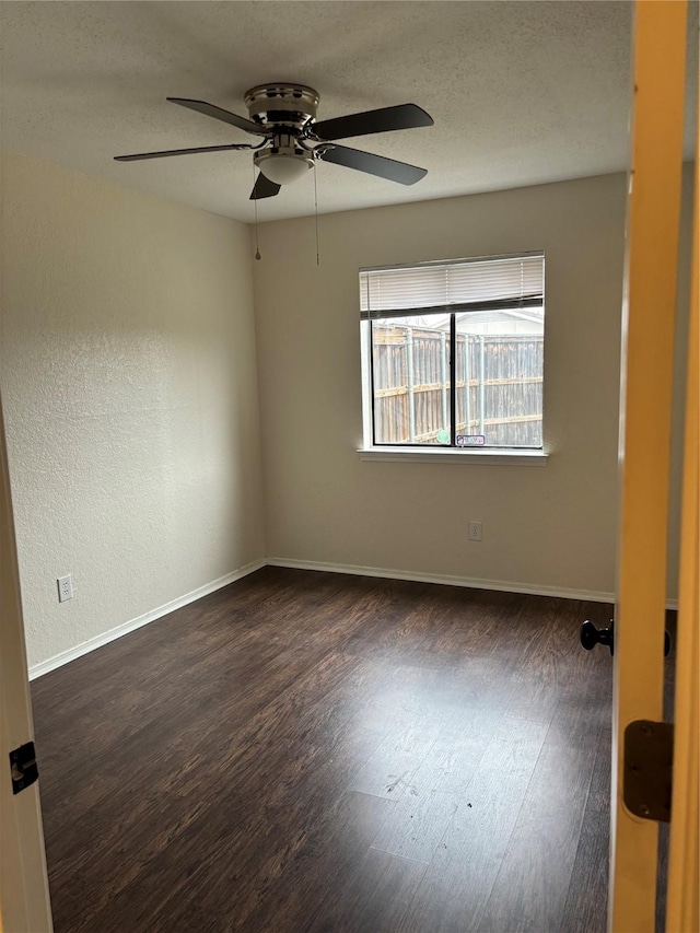 empty room with a ceiling fan, a textured ceiling, baseboards, and dark wood-style flooring