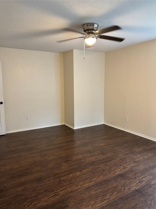 empty room featuring a textured ceiling, ceiling fan, dark wood-type flooring, and baseboards