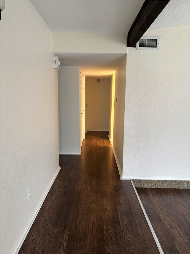 hall featuring baseboards, beam ceiling, visible vents, and wood finished floors