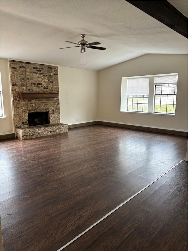 unfurnished living room with ceiling fan, lofted ceiling, dark wood-type flooring, baseboards, and a brick fireplace