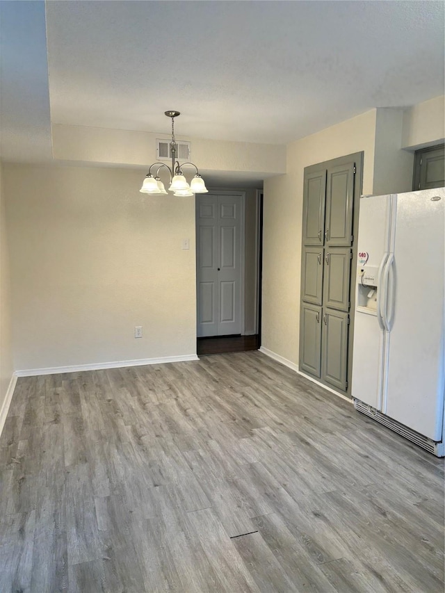 unfurnished dining area with baseboards, visible vents, a notable chandelier, and light wood finished floors