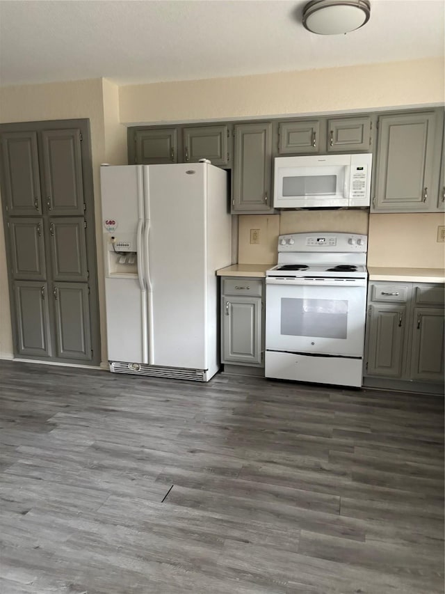 kitchen featuring gray cabinets, light countertops, white appliances, and dark wood-type flooring