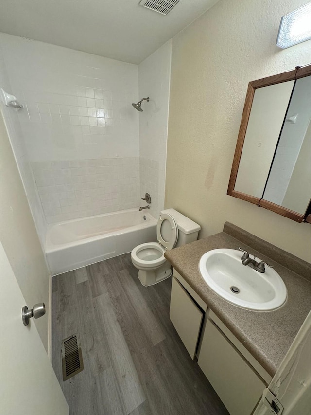 full bath with visible vents, toilet, wood finished floors, vanity, and shower / washtub combination