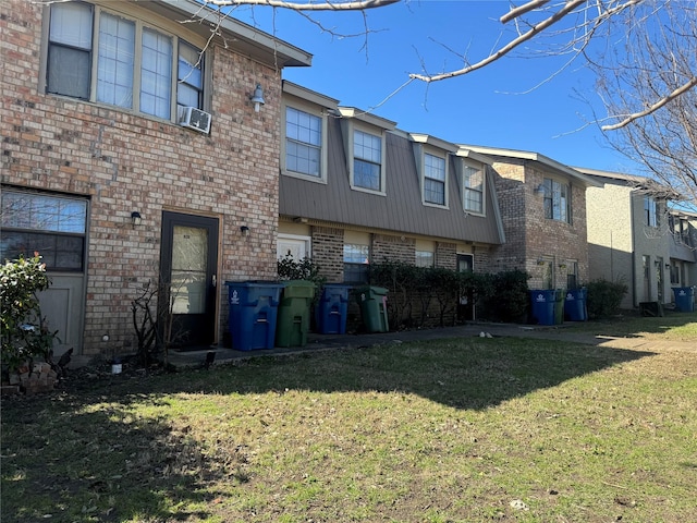 back of house with a lawn and brick siding