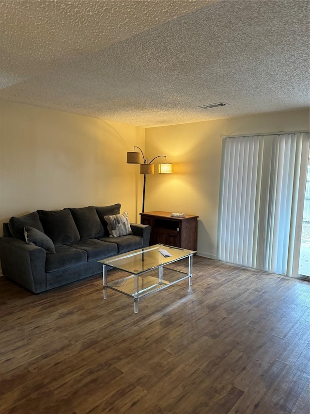 living area with a textured ceiling, visible vents, and wood finished floors