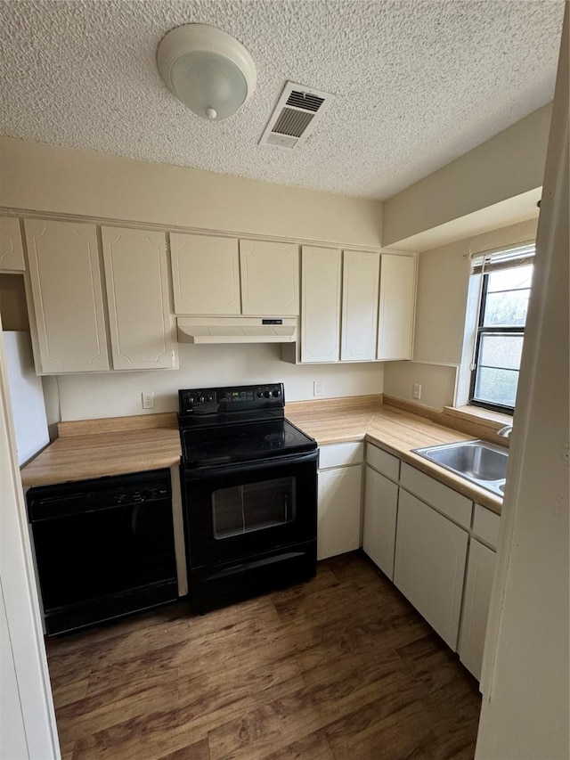 kitchen featuring visible vents, white cabinets, under cabinet range hood, black appliances, and a sink