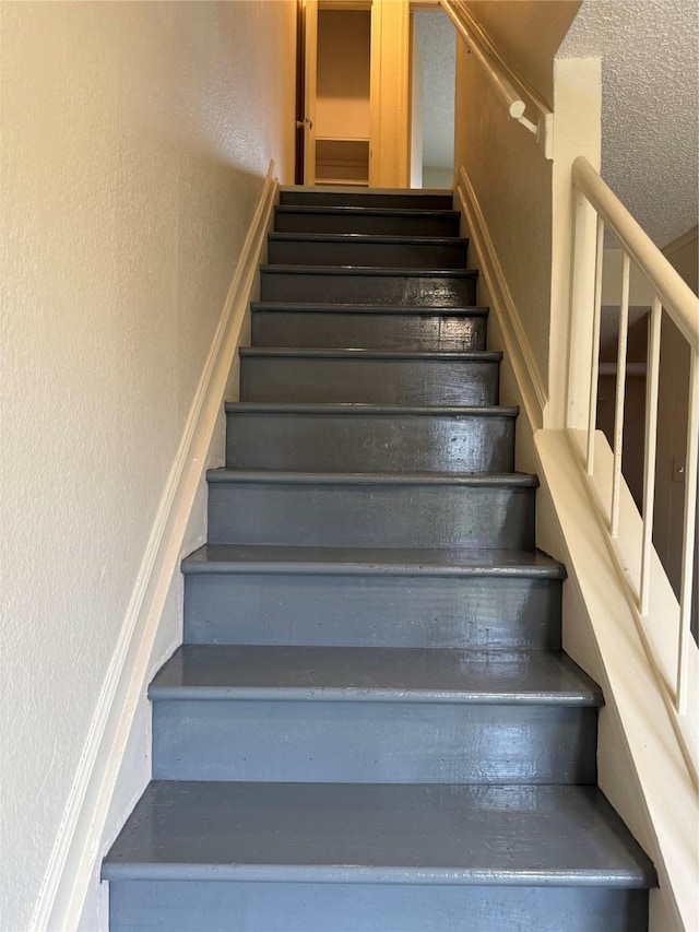 staircase featuring a textured wall