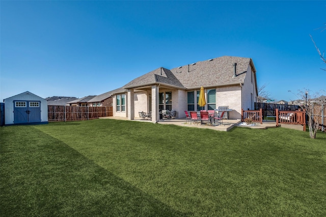 rear view of property with a storage unit, a lawn, a fenced backyard, an outdoor structure, and brick siding