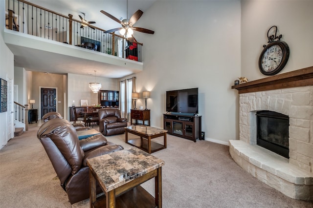 living area with light carpet, a ceiling fan, a stone fireplace, baseboards, and stairs