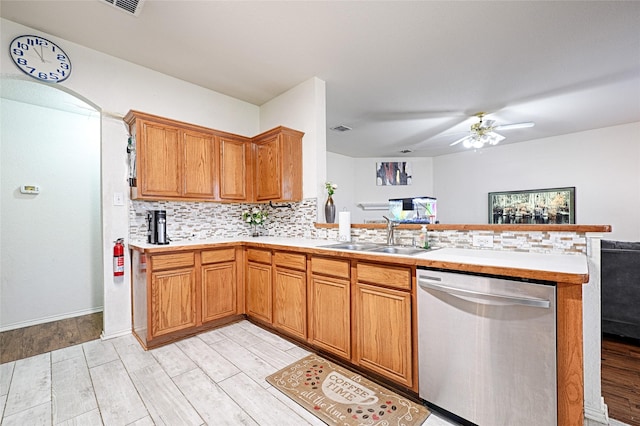 kitchen featuring a peninsula, a sink, open floor plan, light countertops, and stainless steel dishwasher