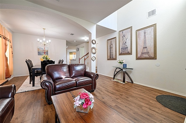 living room featuring a chandelier, arched walkways, baseboards, and wood finished floors