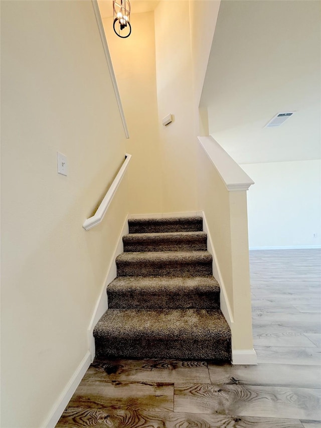 stairs with wood finished floors, visible vents, and baseboards