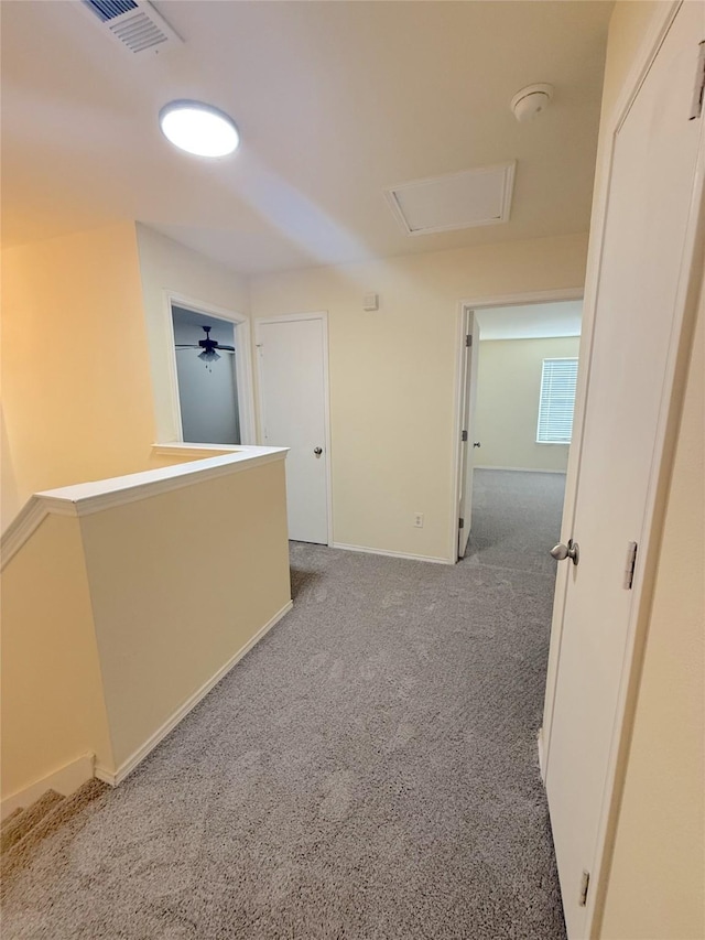 hallway with attic access, baseboards, visible vents, carpet flooring, and an upstairs landing