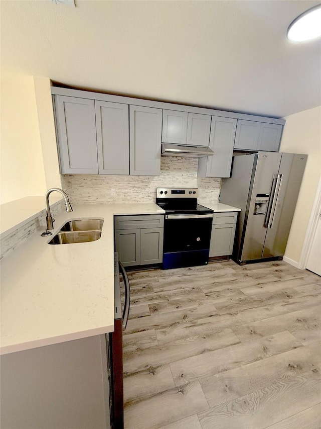 kitchen with electric stove, stainless steel fridge with ice dispenser, gray cabinets, under cabinet range hood, and a sink