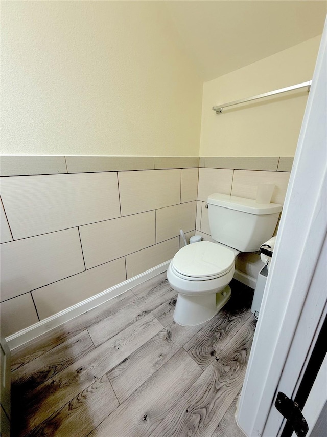 half bathroom featuring toilet, a wainscoted wall, and wood finished floors