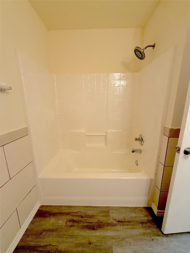 bathroom with wainscoting, shower / washtub combination, tile walls, and wood finished floors