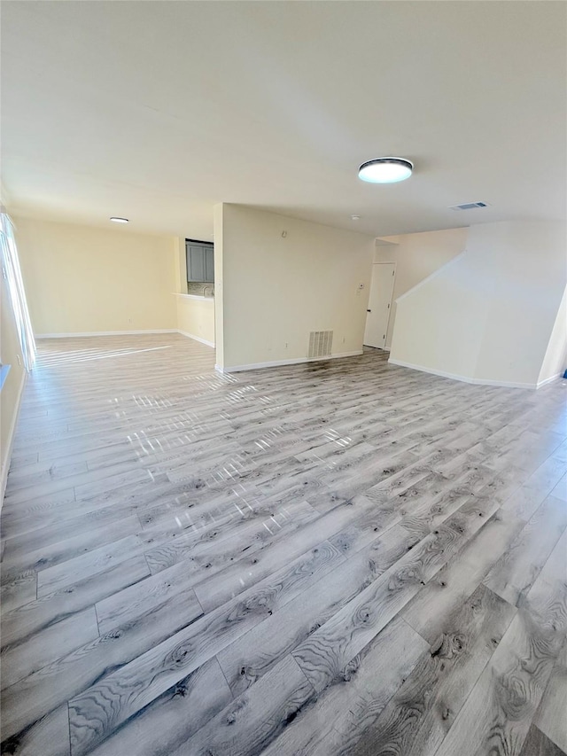 unfurnished living room featuring light wood-style flooring, visible vents, and baseboards