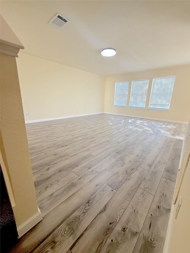 empty room featuring baseboards, visible vents, and wood finished floors