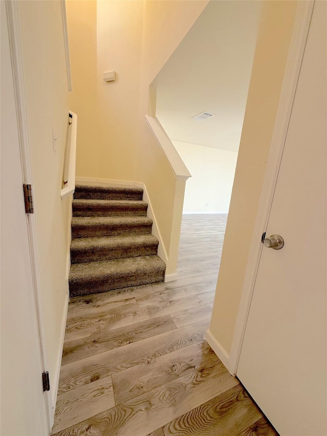 stairs with visible vents, baseboards, and wood finished floors