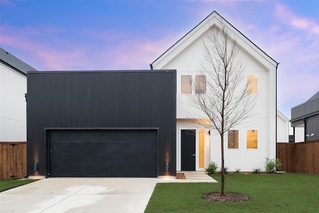 view of front facade with stucco siding, a lawn, driveway, fence, and a garage