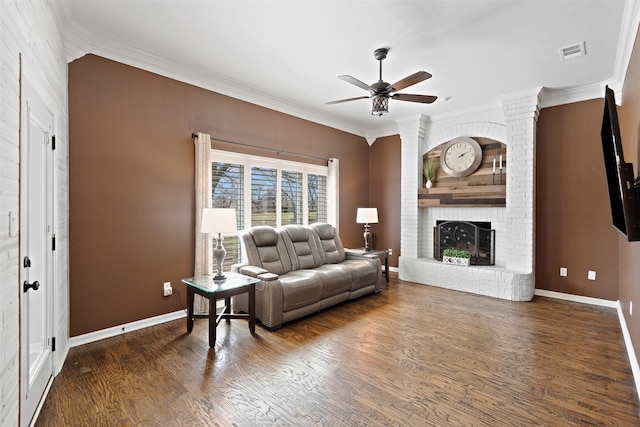 living room featuring baseboards, a ceiling fan, wood finished floors, crown molding, and a fireplace