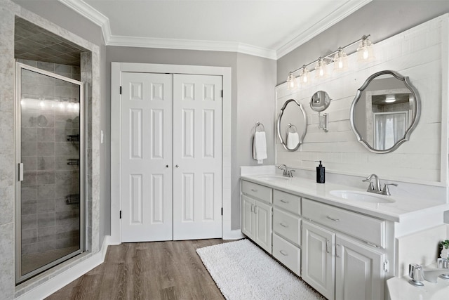 full bath featuring wood finished floors, a stall shower, a sink, and crown molding