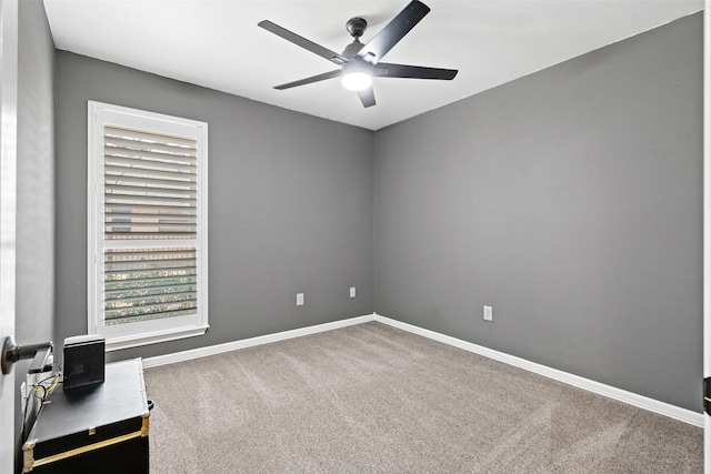 carpeted empty room with a ceiling fan and baseboards