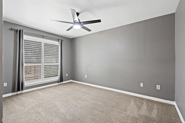 carpeted empty room featuring ceiling fan and baseboards