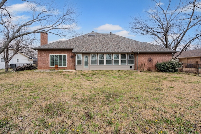 back of house featuring a yard, brick siding, a chimney, and a fenced backyard