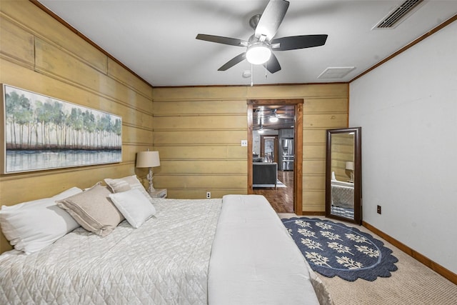 bedroom featuring crown molding, visible vents, a ceiling fan, wooden walls, and baseboards