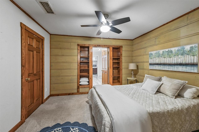 carpeted bedroom featuring wood walls, baseboards, visible vents, and crown molding