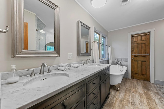 bathroom featuring double vanity, wood finished floors, a sink, and crown molding