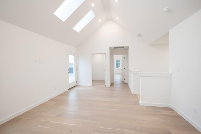 spare room featuring light wood-style flooring, high vaulted ceiling, visible vents, and a skylight