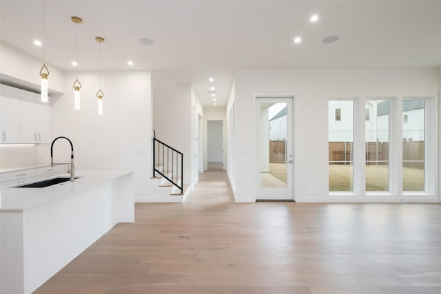 kitchen with light wood finished floors, plenty of natural light, white cabinetry, and a sink