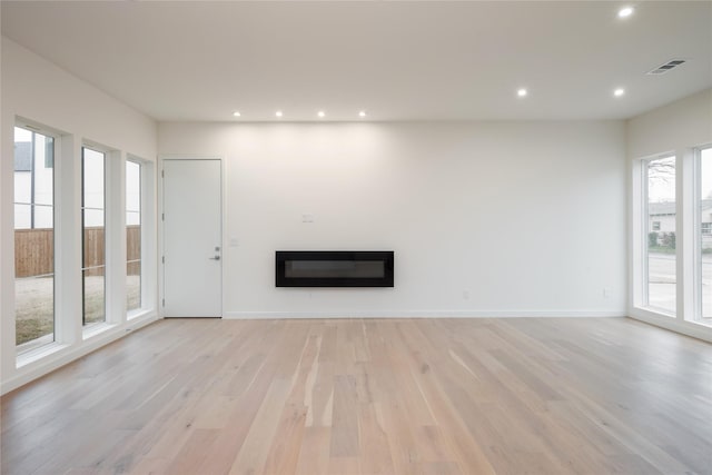 unfurnished living room featuring visible vents, a glass covered fireplace, recessed lighting, light wood finished floors, and baseboards