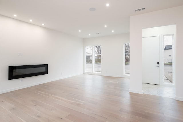 unfurnished living room with recessed lighting, light wood-type flooring, and baseboards