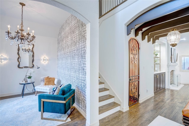 interior space with arched walkways, a notable chandelier, wood finished floors, baseboards, and stairs