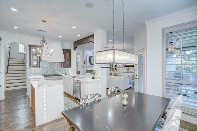 62 Cypress Ct, Trophy Club, TX 76262 - dining space featuring a chandelier, crown molding, arched walkways, stairway, and wood finished floors