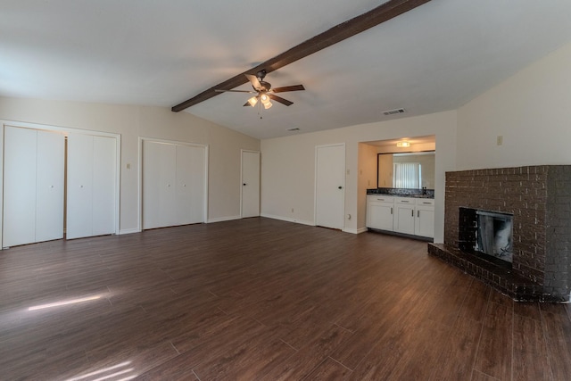 unfurnished living room with vaulted ceiling with beams, a fireplace, visible vents, and dark wood-style flooring