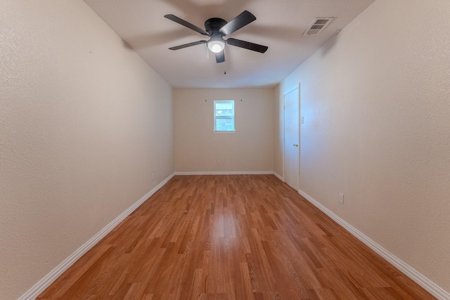 unfurnished room with light wood-type flooring, baseboards, visible vents, and a ceiling fan