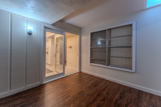 empty room featuring a textured ceiling, baseboards, and wood finished floors