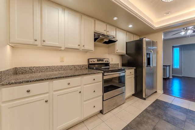 kitchen with a raised ceiling, appliances with stainless steel finishes, white cabinets, ceiling fan, and under cabinet range hood