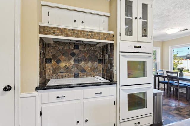 kitchen with white appliances, dark countertops, white cabinetry, and decorative backsplash