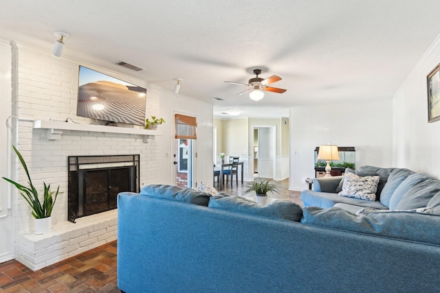 living room with a fireplace, a ceiling fan, visible vents, baseboards, and ornamental molding