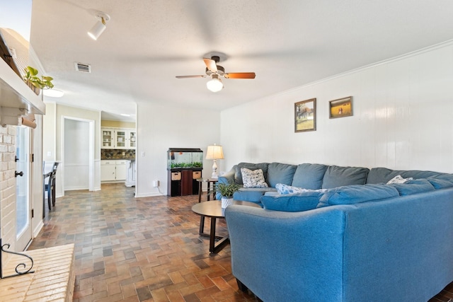 living area with brick floor, visible vents, and ceiling fan